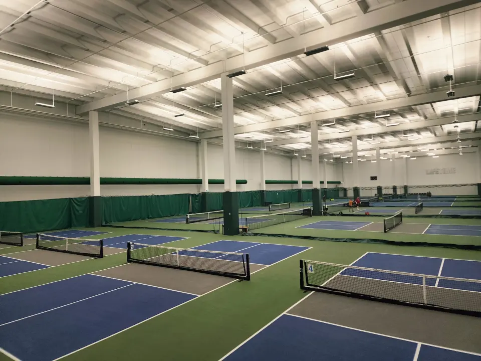 Indoor pickleball courts under a high ceiling