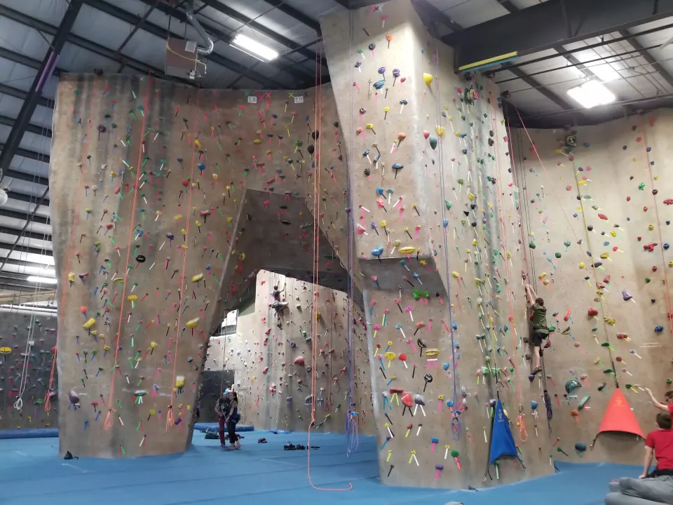 Tan roped walls around the lead arch, with top ropes hanging over blue flooring