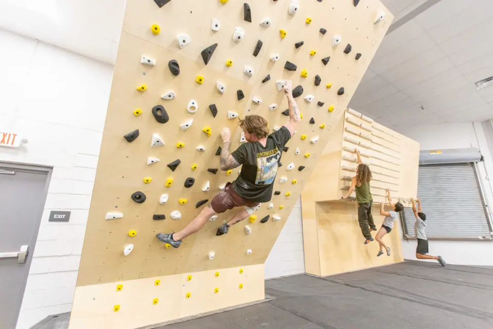 Climber on the MoonBoard next to the wooden training wall