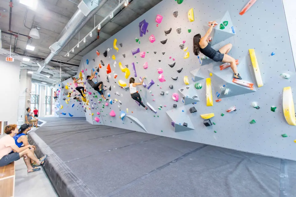 Long grey bouldering wall with colourful holds and volumes above thick matting