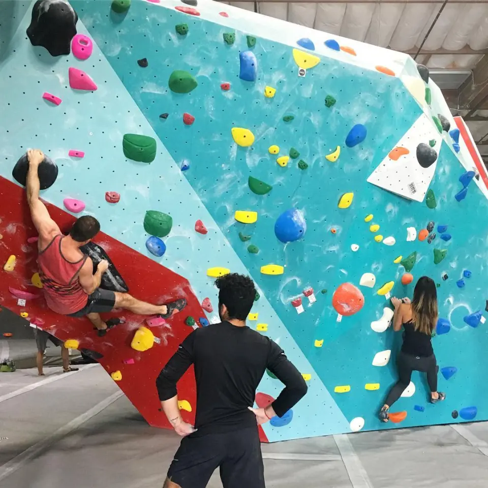 Climbers on a teal and red bouldering wall