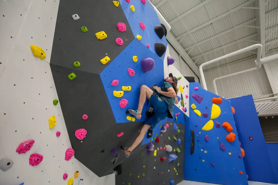Climber on a grey and blue boulder