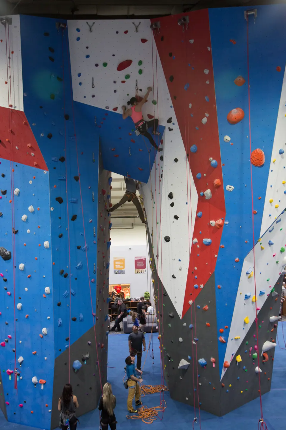 Climbers on a red, white and blue roped tower