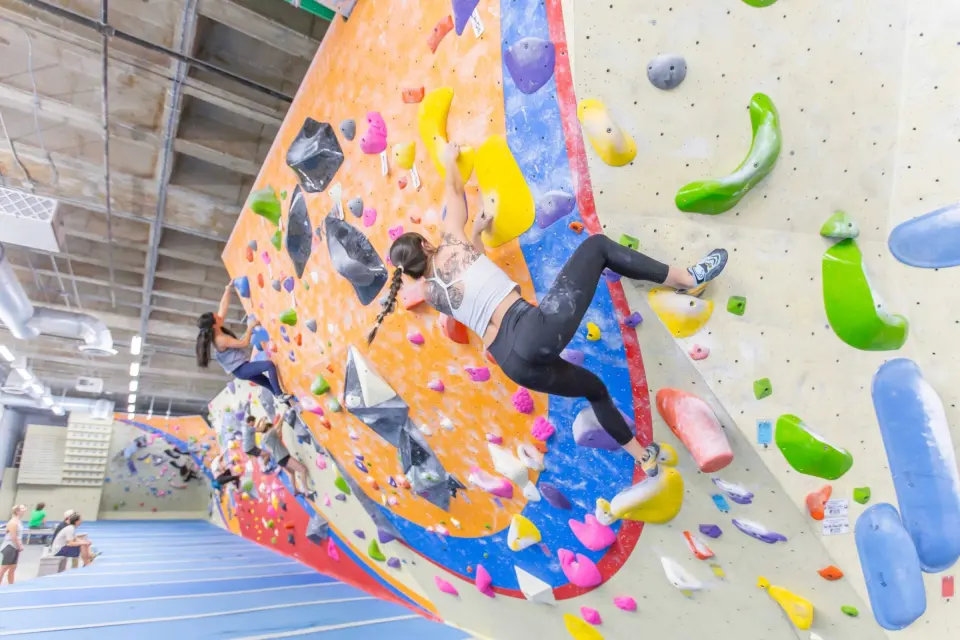 Climber on the orange and blue overhanging bouldering wall