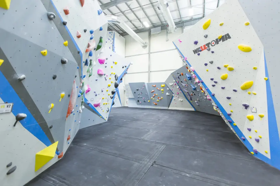 Grey and blue bouldering walls around a matted floor