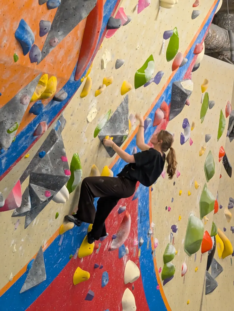 Climber on a colourful vertical bouldering panel