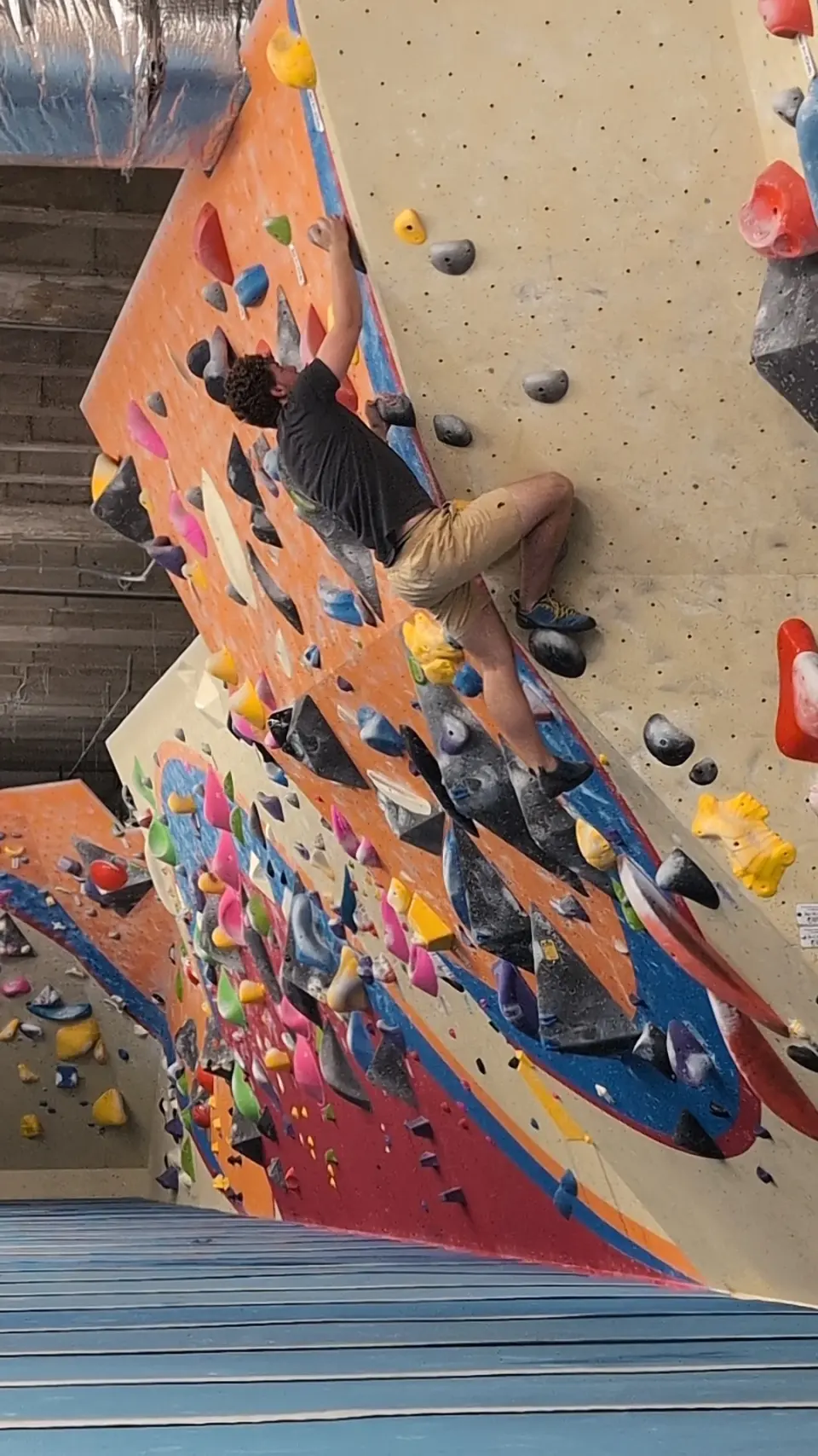 Long red and orange bouldering wall with climbers
