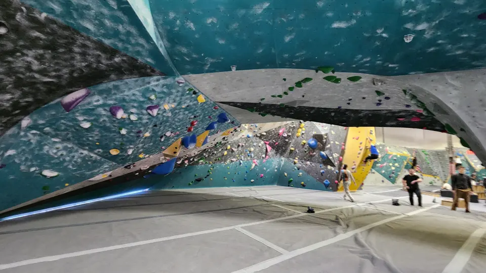 Wide view of the bouldering hall under the big teal overhang