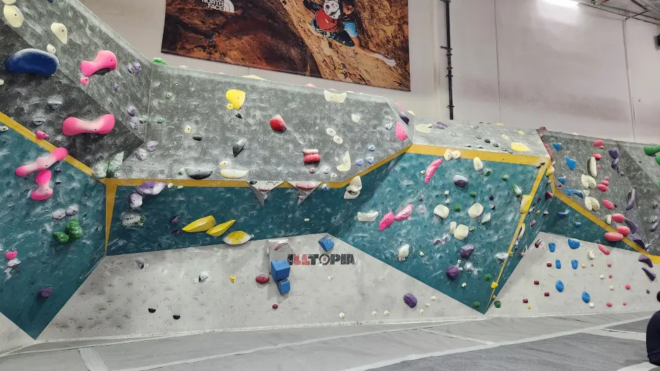 Long teal and grey bouldering wall with a slab section