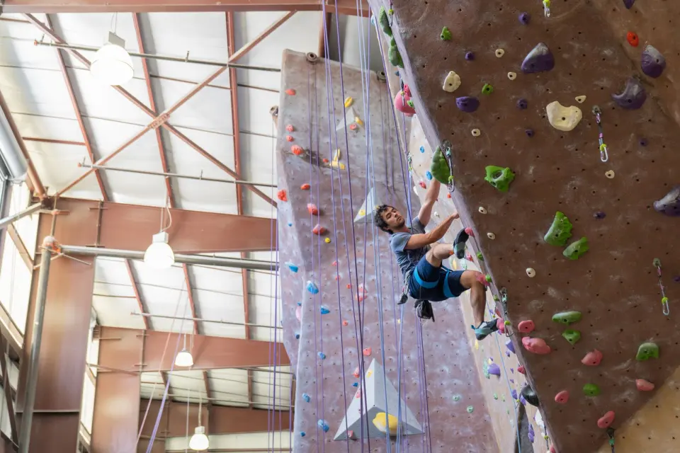 Lead climber on a steep wall below the roof trusses