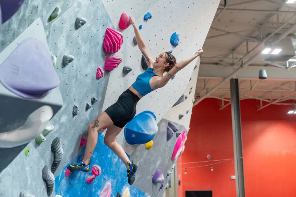 Climber on a grey bouldering wall set with pink holds
