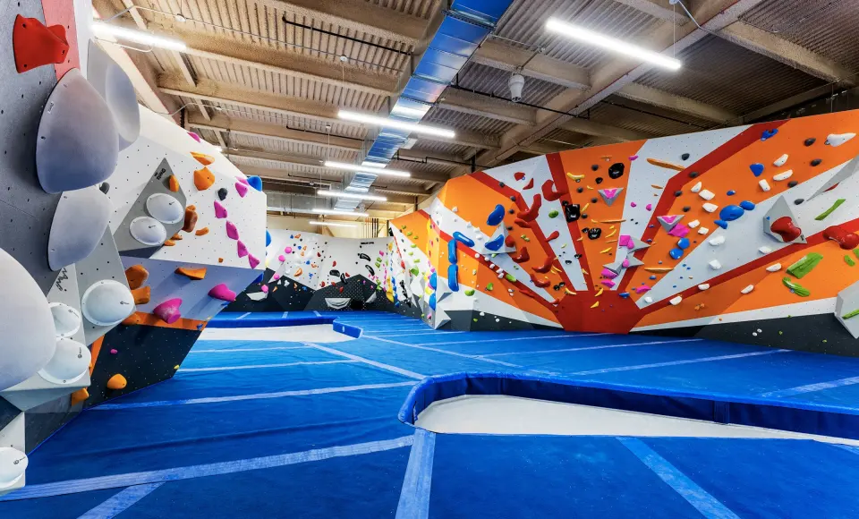 Bouldering floor with an orange sunburst wall and blue matting