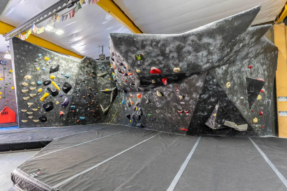 Bouldering wall with a large grey volume above thick matting