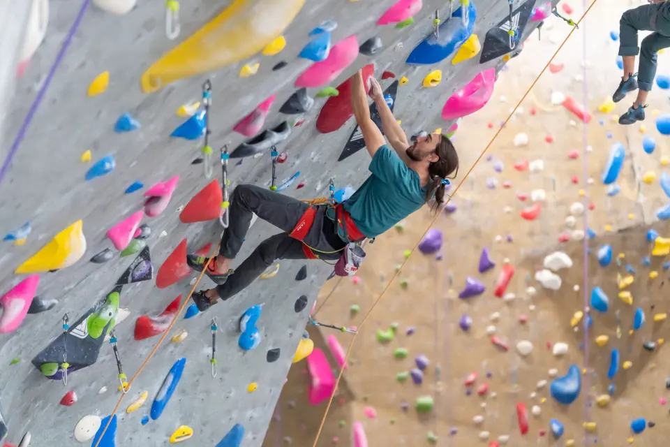Climber on a top rope among colourful holds