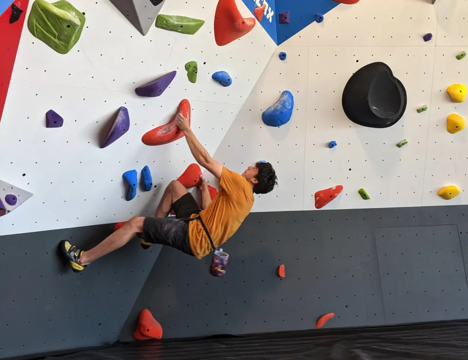 Climber on a white bouldering wall with colourful holds