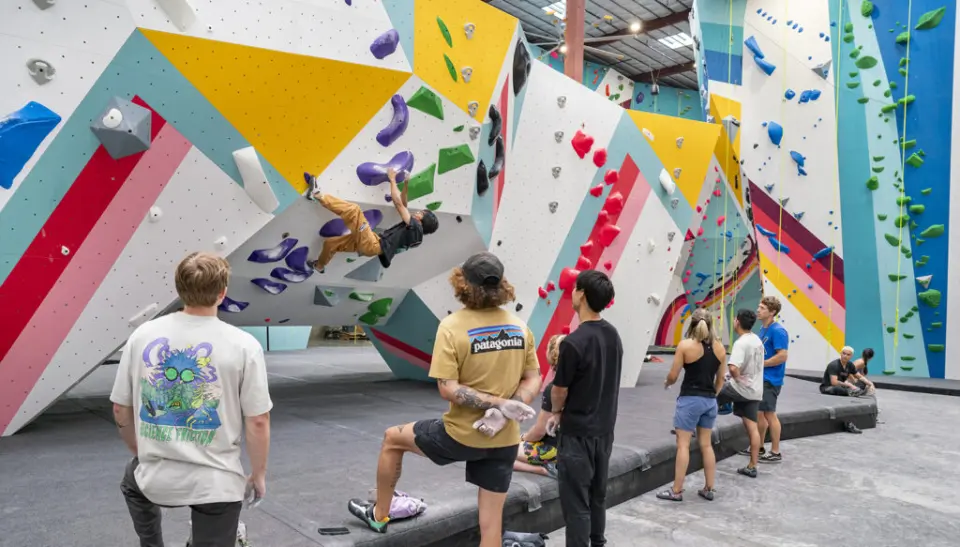 Climbers watching a boulderer on an angular wall