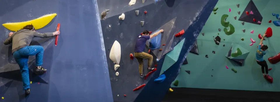 Three climbers on blue and mint walls with large volumes