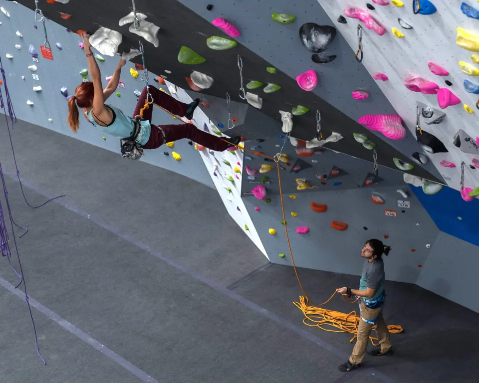Lead climber on an overhanging wall while her belayer pays out rope