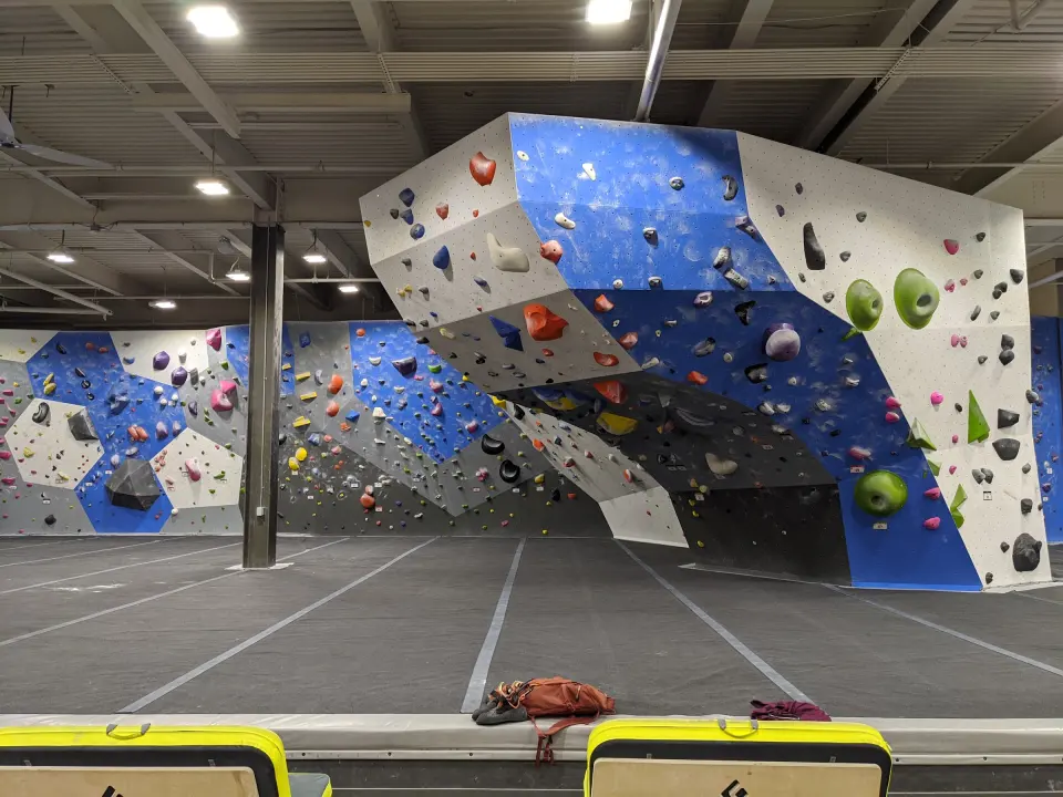 Blue and white bouldering wall with a large overhanging prow