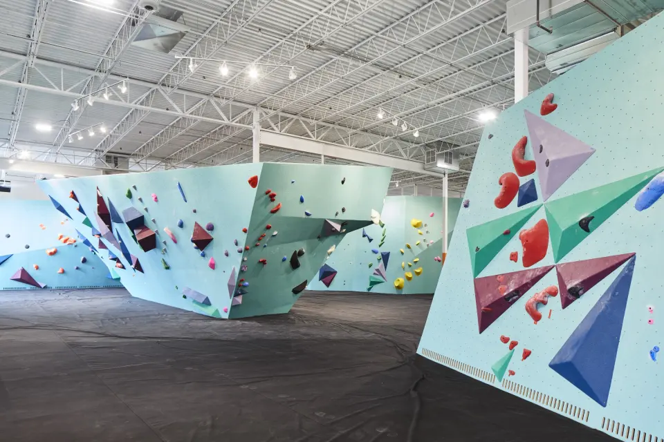 Teal bouldering walls covered in geometric volumes across the main floor
