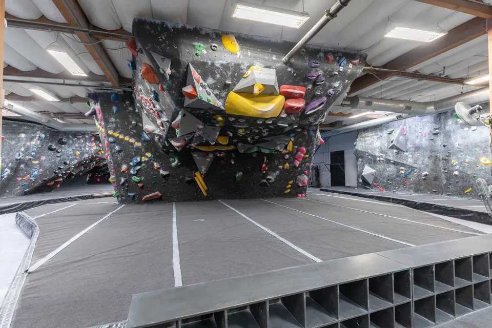 Looking up at the overhanging roof boulder with yellow and red volumes