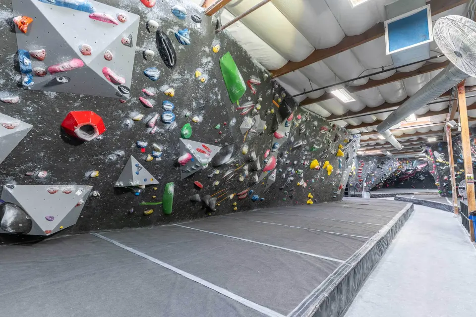 Bouldering wall with grey triangular volumes and colourful holds