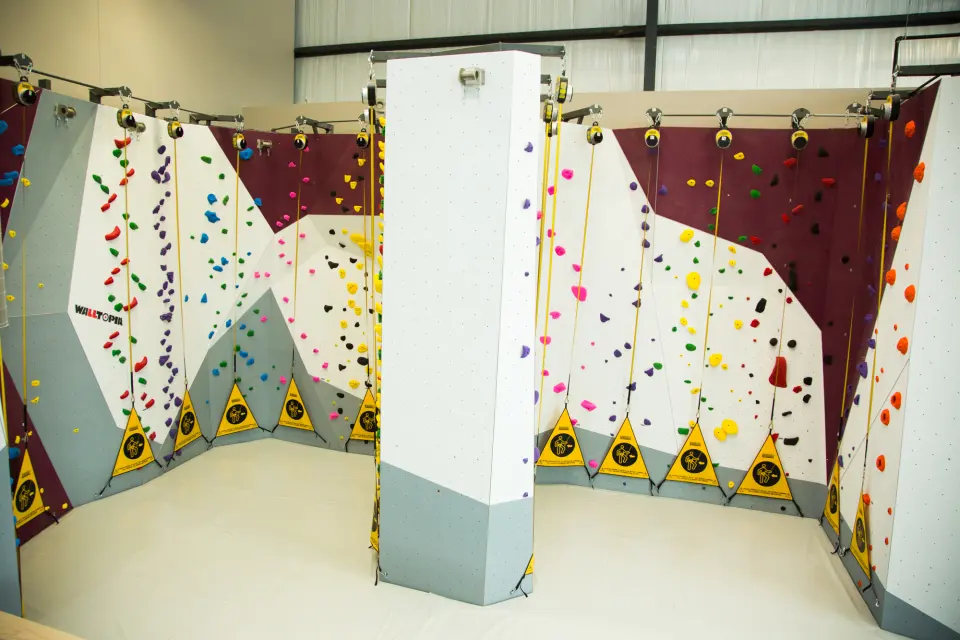 Row of auto-belay lanes on maroon and white walls