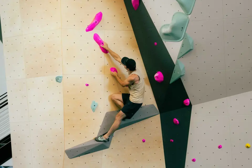 Climber standing on a grey volume on the bouldering wall