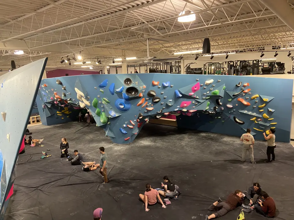 Long overhanging blue bouldering wall seen from the mezzanine