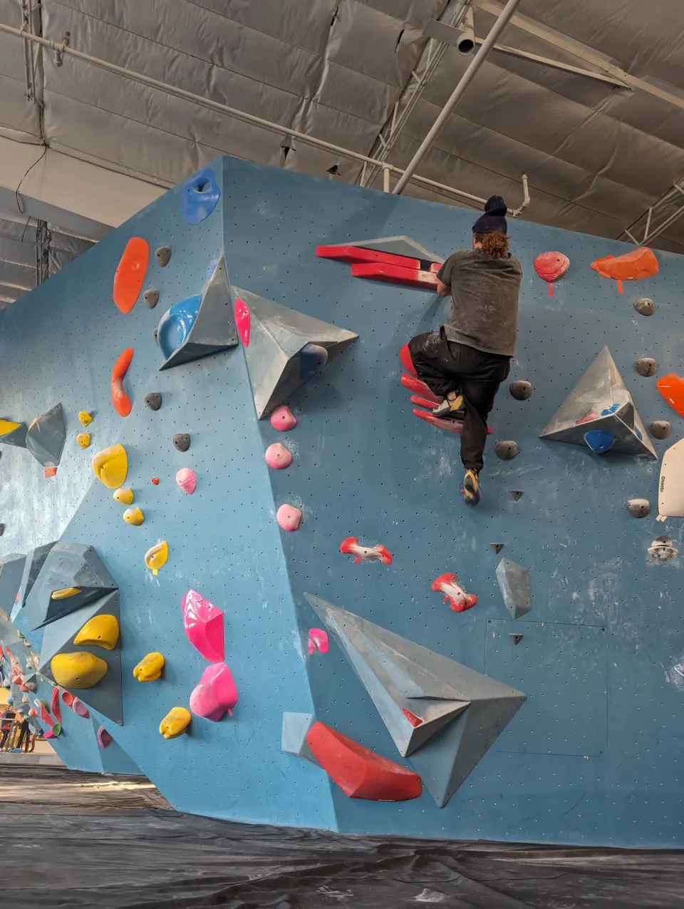 Climber on an overhanging boulder with red and pink holds