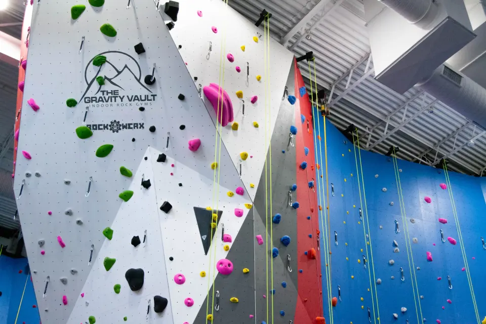 Top-rope lines on the white and grey wall carrying the Gravity Vault logo