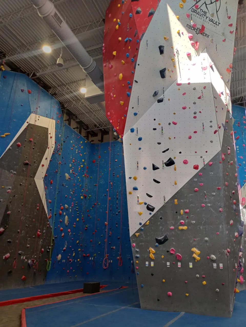 Tall grey and white climbing pillar in front of the blue rope walls