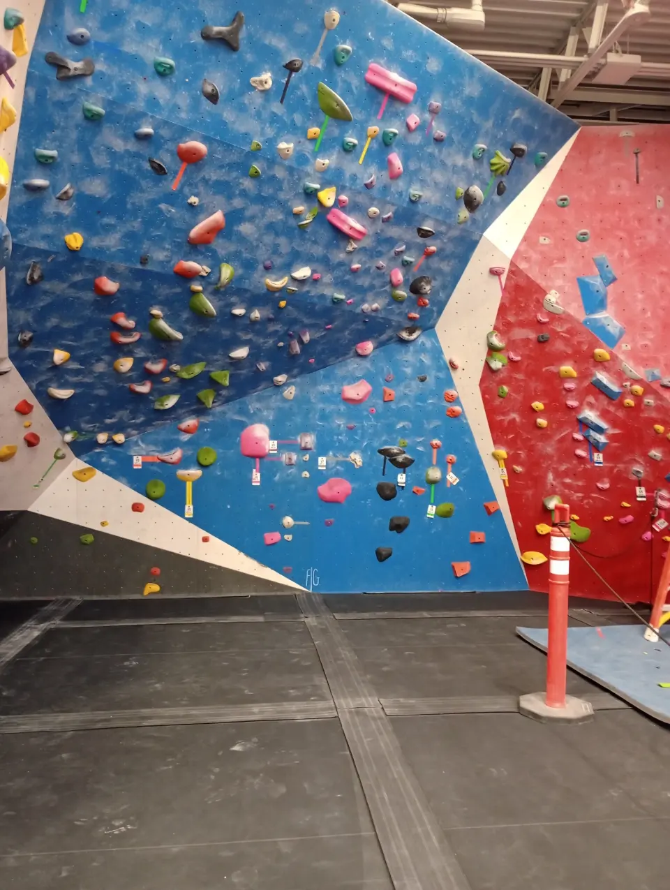 Steep blue and red bouldering wall covered in holds