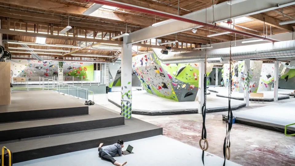 Stepped seating and gymnastic rings looking across the bouldering floor