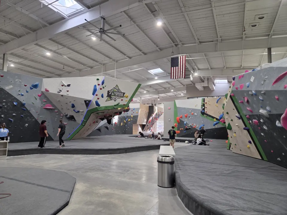 Grey and white bouldering walls with green edges across the large main hall
