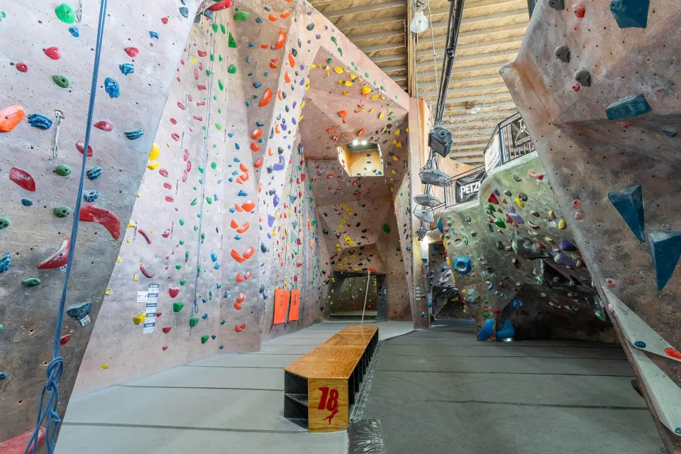 Tall rope walls with lead lines beside the bouldering area under the hangar roof