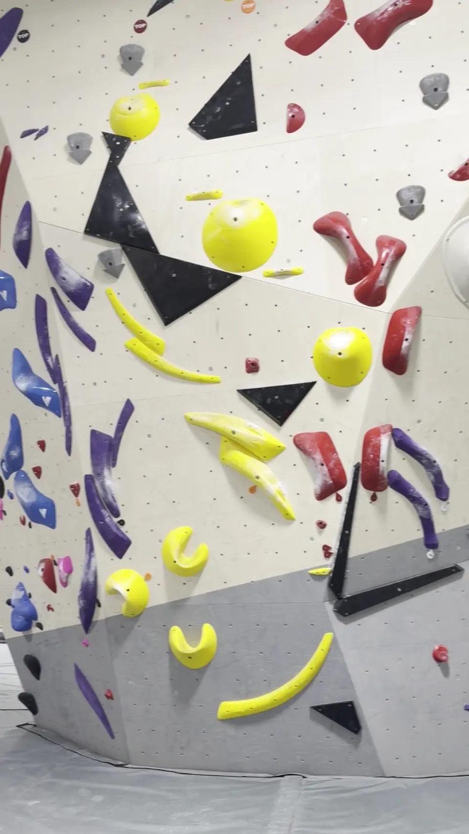 Yellow, red and black volumes and holds on a bouldering wall