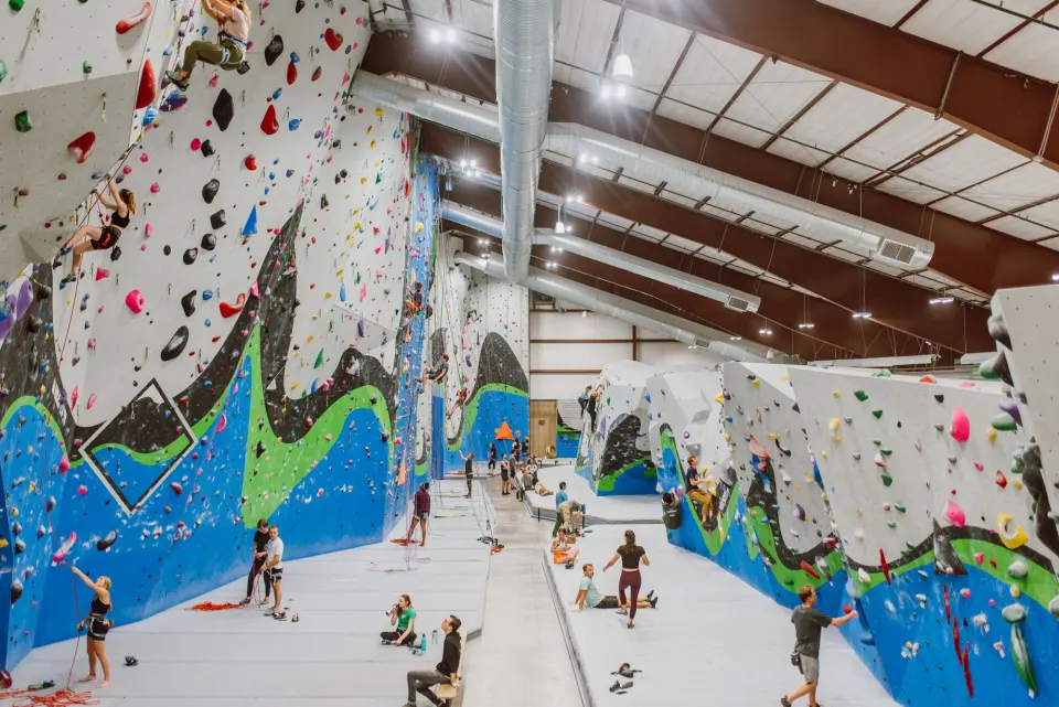 Long hall of blue, green and grey roped walls with bouldering walls on the right