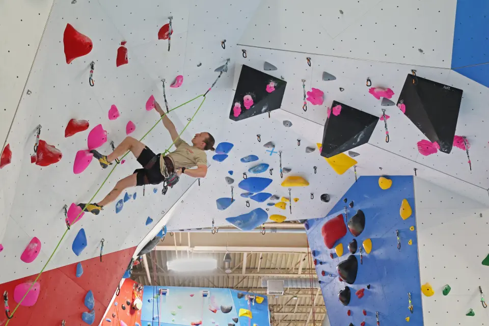 Lead climber clipping on the steep overhanging wall