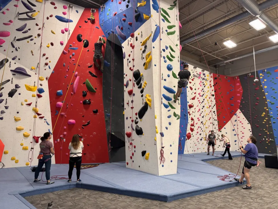 Belayers and climbers around a freestanding rope pillar