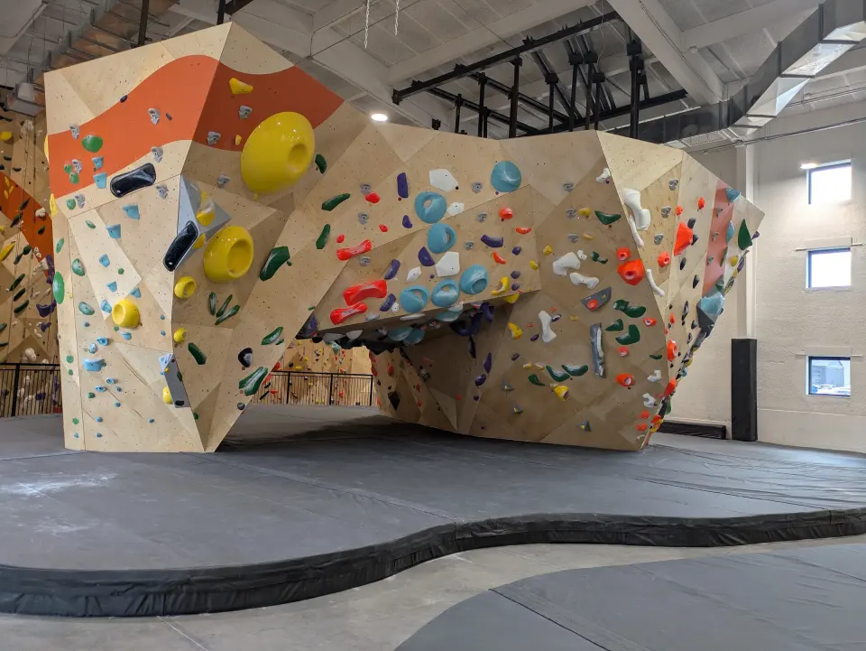 Large plywood arch boulder with an orange band, standing on grey matting