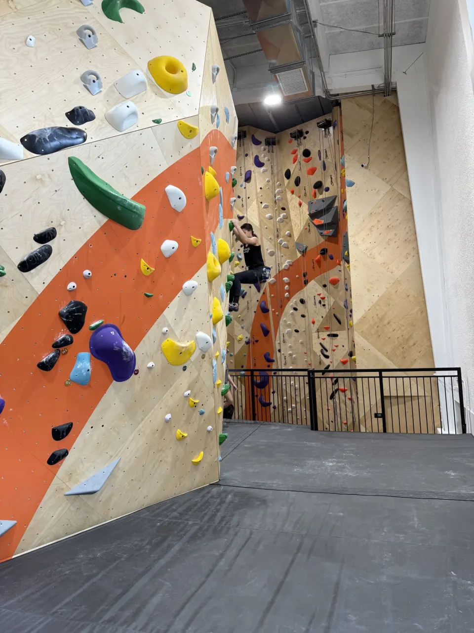 Bouldering wall with an orange band below the mezzanine railing