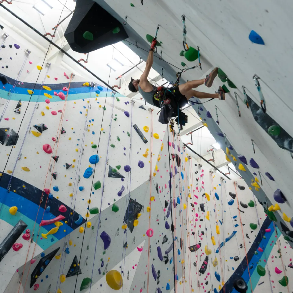 Lead climber high on a steep wall above the blue stripes