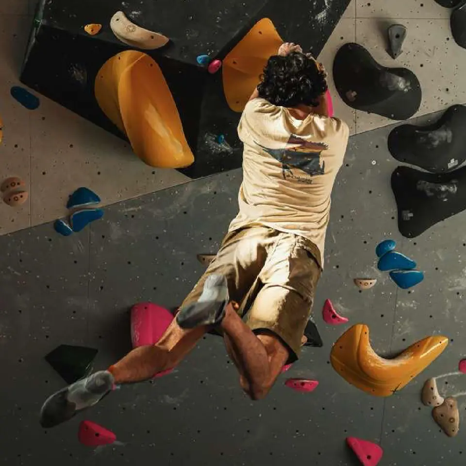 Boulderer reaching between big yellow holds on an overhang