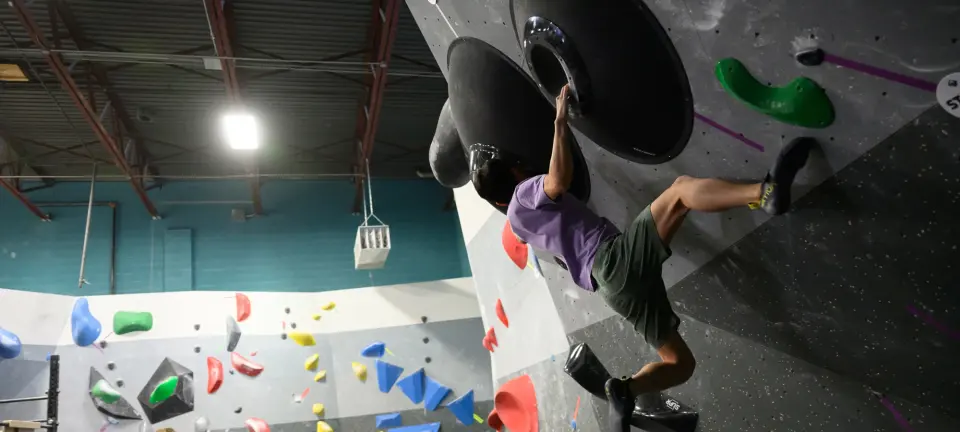 Climber pulling through a steep overhang on large black holds