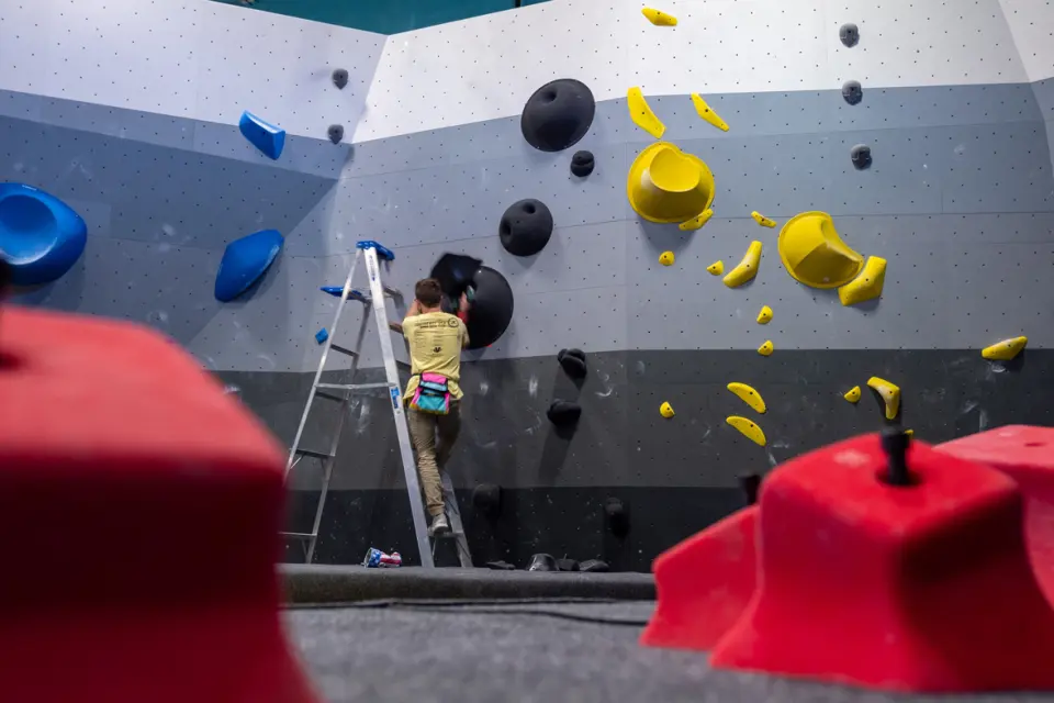 Routesetter on a ladder setting a boulder with yellow holds