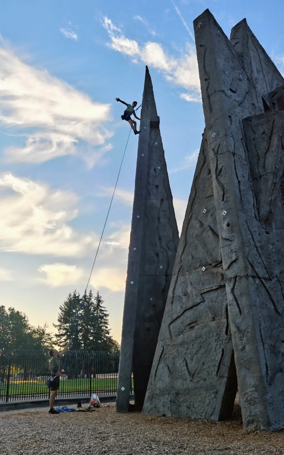 Climber on a rope near the top of a spire at sunset