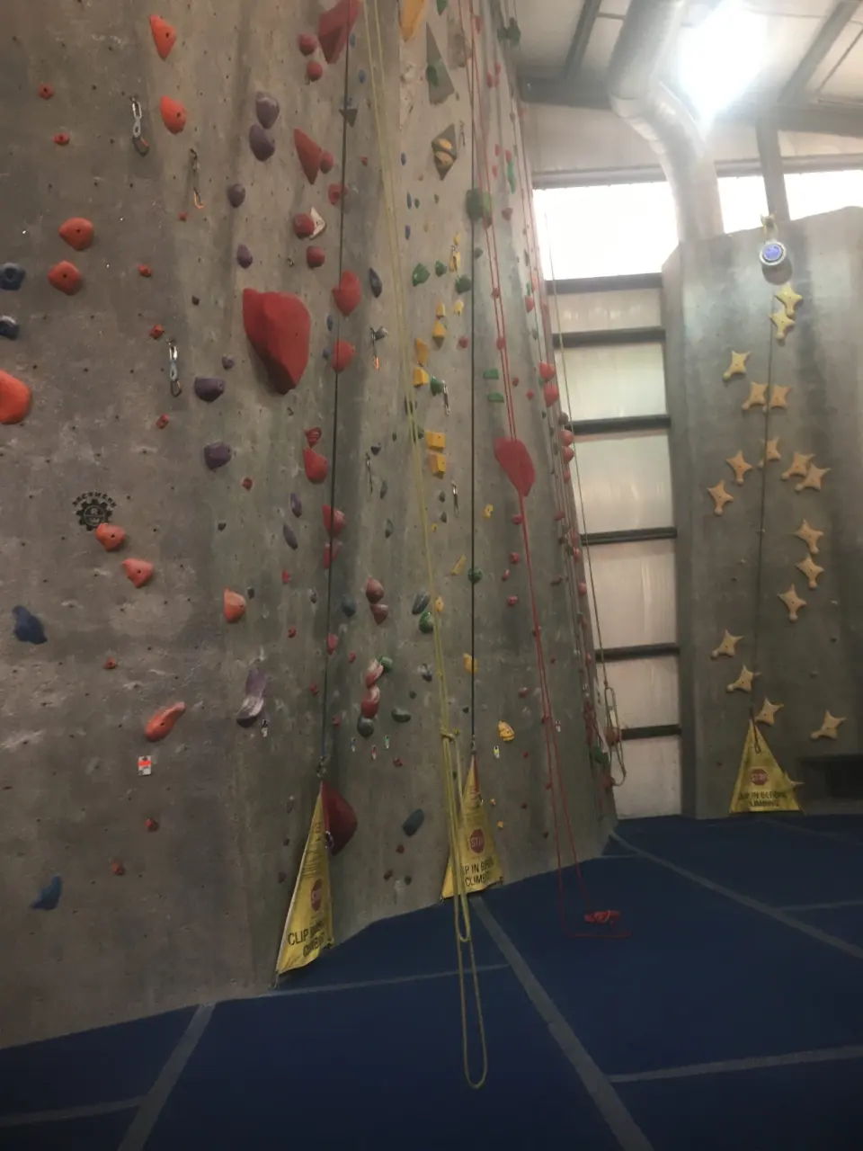 Rope lanes with auto-belays below the grey walls
