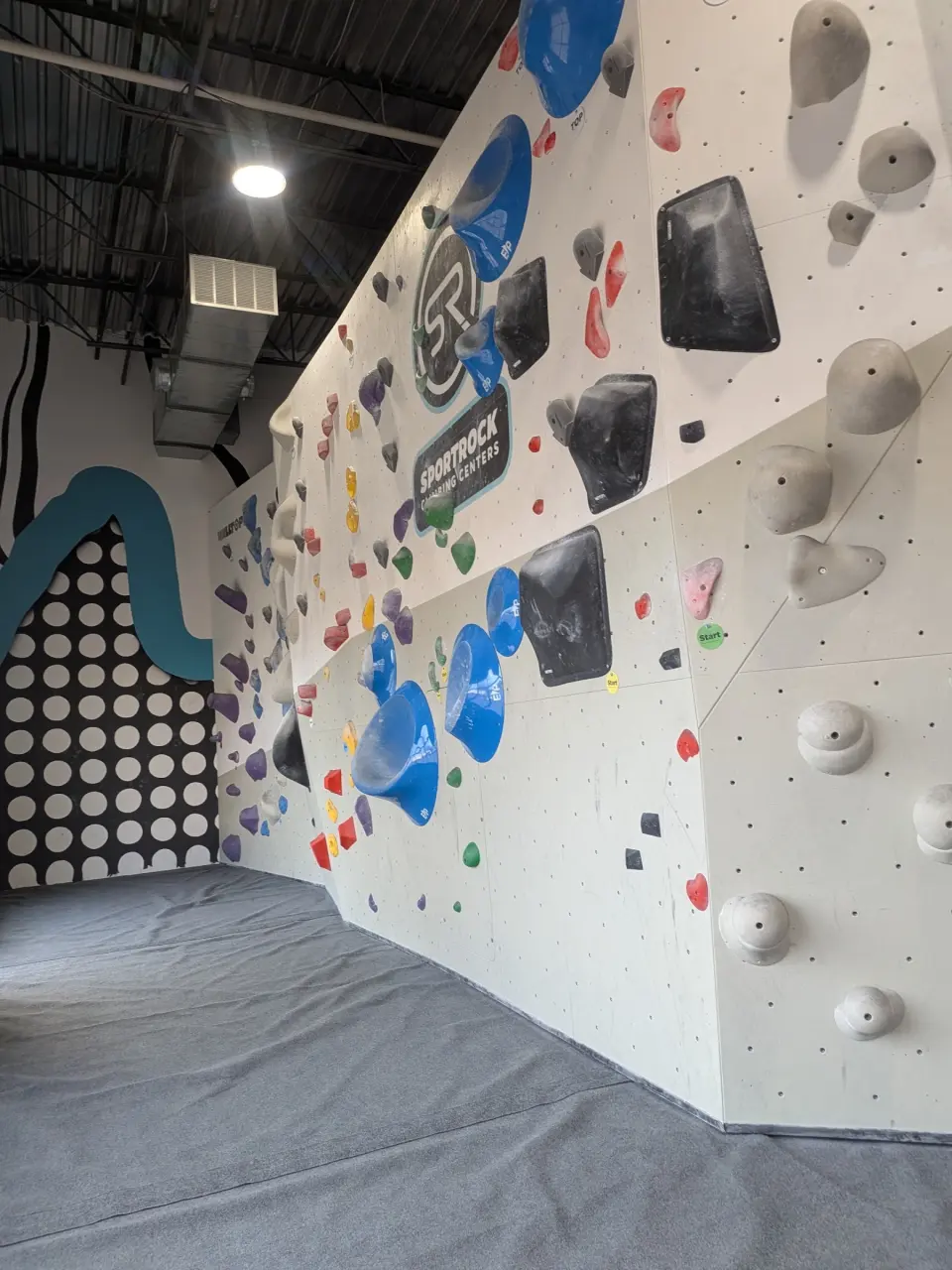 White bouldering wall with blue volumes under the Sportrock logo