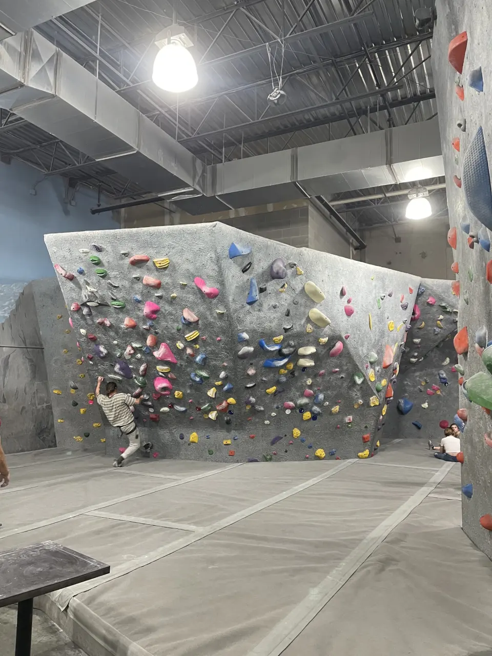 Overhanging grey boulder packed with pink and yellow holds